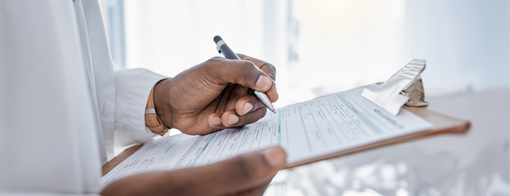 Medical professional from shoulders down writing on a form on a clipboard